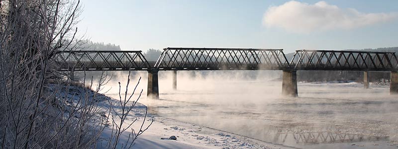 Train bridge with ice fog coming off the river in winter.