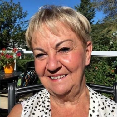 Woman with short gray hair wearing a black and white polka dot shirt.