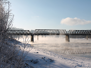 Railway bridge in Quesnel BC on a sunny winter day with river fog.
