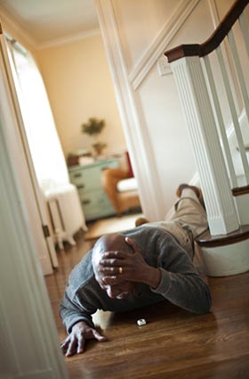 Man lying on his house floor with lifeline button around his neck