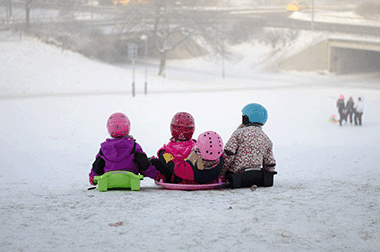 3 Kids sledding on a foggy winter day.