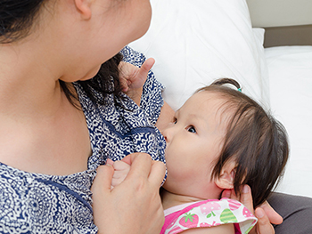 Mother in blue shirt breastfeeding toddler