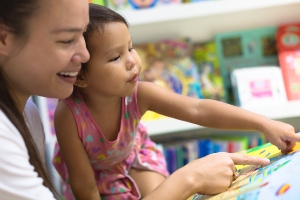 Woman looking at a book with a young child.