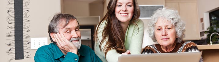 Young woman showing an elderly couple how to access HealtheLife records on a laptop computer