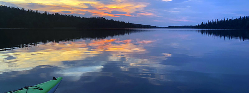 Lake at sunset with green kayak.