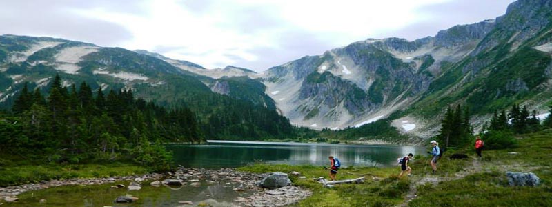 4 hikers at a mountain lake.