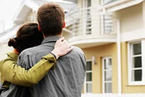 Embacing couple standing in garden and looking at their home